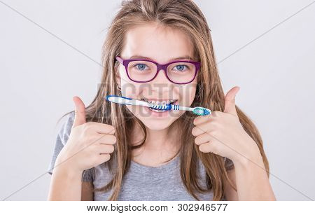 Girl From The Dental Braces With Teethbrush Making Thumb Up Hand Sign Gesture. Orthodontist And Dent