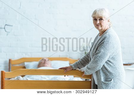 Upset Senior Woman And Man In Coma In Clinic