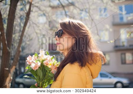 Outdoors Portrait Of Stylish Attractive Brunette Woman In Sunglasses Walking Outdoors With Big Bouqu