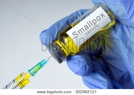 Hands In Blue Gloves Are Typing A Yellow Vaccine In A Syringe. Smallpox Vaccination Concept. Close-u