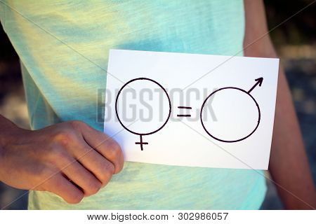 Gender Equality Concept, A Piece Of Paper With A Female And A Male Symbol In A Woman's Hand