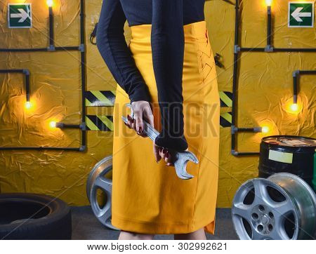 Stylish Mechanic Girl In Trendy Clothes Is Holding A Wrench On The Background Of The Workshop Of An 
