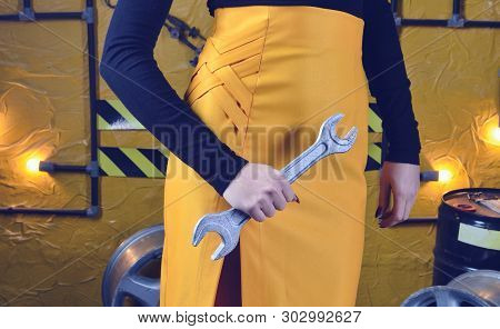 Fashionable Mechanic Girl In Trendy Clothes Is Holding A Wrench On The Background Of The Workshop Of