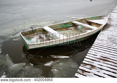 Old Green Boat In A Frozen Lake. The Boat Is Covered With Snow. Water Froze Inside The Boat. Low Tem