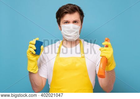Young Seious Man In Apron, Protective Mask And Gloves Ready To Clean Everything From Coronavirus.