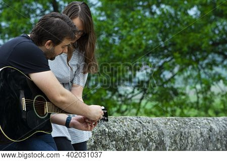 Older Brother Teaching His Younger Sister To Play Guitar In The Nature. Beautiful Moments Spent Toge