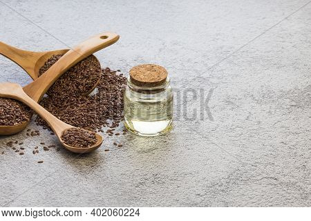 A Jar Of Linseed Oil Flax Seeds In A Wooden Spoon On A Concrete Background, A Dietary Cereal Ingredi