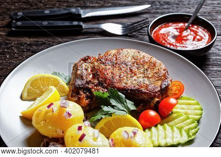 Roasted Pork Karbonade, Pork Cutlets With Boiled Potato And Sliced Cucumber And Lemon On A Plate On 