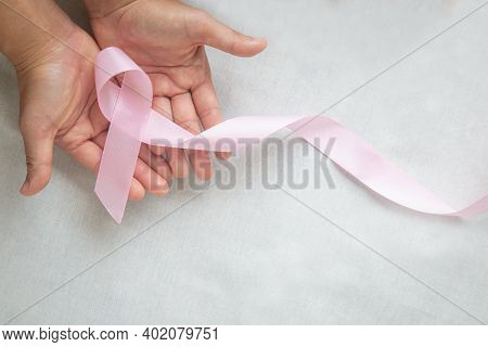 Hands Holding Pink Ribbon Curl On White Isolated Fabric With Copy Space. Breast Cancer Awareness, Ma