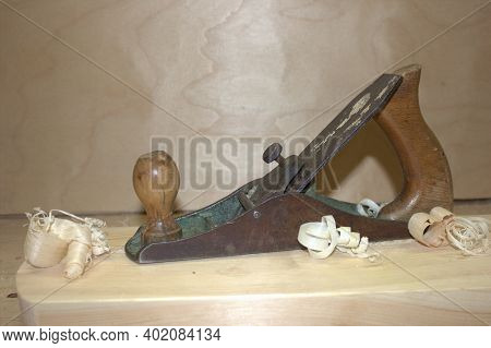 An Old Hand Jack Plane On A Wooden Table, Next To A Wooden Sawdust In The Workshop. Carpenter Tools.
