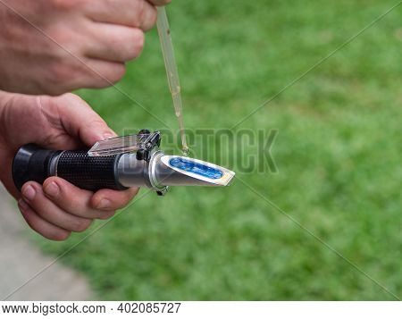 Close-up Of Hands Young Man Holding Refractometer For Measure Craft Beer Sugar Level. Selective Focu