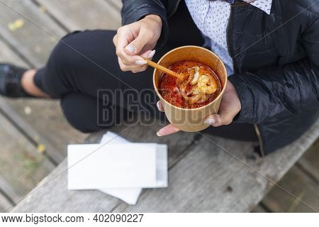 The Girl On The Bench Eats Soup With Seafood Shrimp.