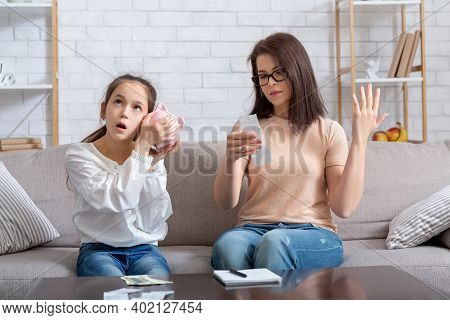 Financial Crisis During Coronavirus Pandemic Concept. Teen Girl With Empty Piggy Bank And Young Moth
