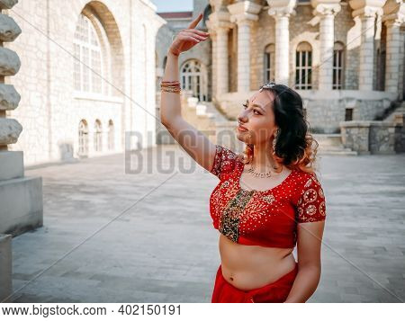 Indian Woman Dance On Streets Of Ancient Architecture City Of India Dressed In Red Sari, Decorated W