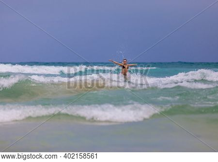 Young Beautiful Girl Enjoys The Sea And The Waves, Laughing Raising Her Hands Up In A Black Fashiona
