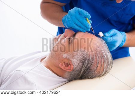 Old man visiting young male doctor in hair transplantation conce