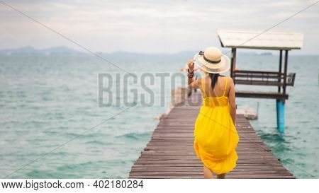 Close Up Portrait Back Young Asian Woman In A Yellow Dress Touching A Hat On Her Head Walking On A W