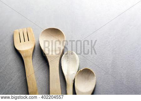 Group Of Wooden Kitchen Utensils Arranged On A Gray Marble Table. Selective Focus On The Carving For