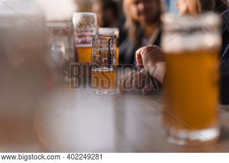 Photo Of Many Glasses Of Beer With Blury People In Background. Photo Was Taken At Beer Festival.