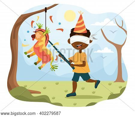 Blindfolded Little Boy Playing Pinata At A Party Trying To Break Open The Donkey Hanging From A Tree