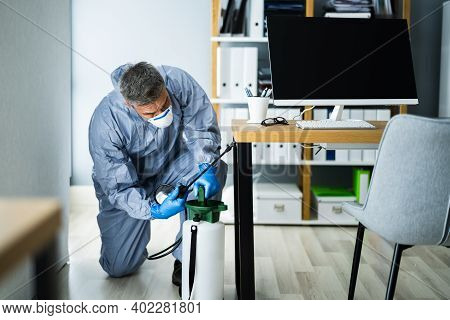 Pest Control Exterminator Man Spraying Termite Pesticide In Office