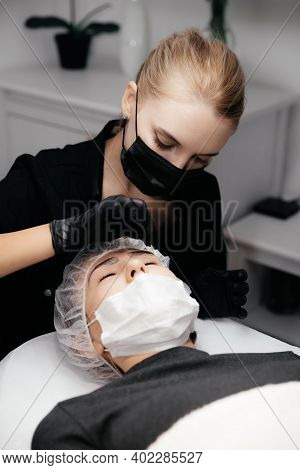 Young Permanent Makeup Artist Removes Anesthetic Cream From The Client's Eyebrows. Master And Client