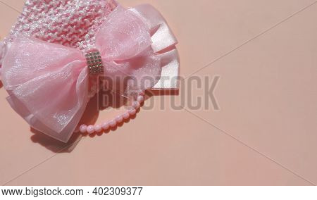 Pink Girl's Bow And Beads On Pastel  Pink  Background,    Children's Flat Lay. Children's Jewelry An
