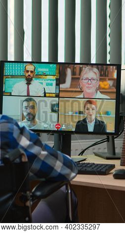 Handicapped Disabled Manager In Wheelchair Talking During Videocall Having Online Conference In Busi