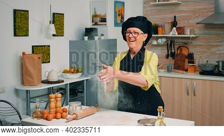 Elderly Chef Standing In Kitchen At Home And Cooking With Enjoyment Bakery Products Of Flour. Profes