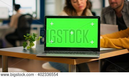 Businesspeople Analysing Annual Financial Reports Sitting At Desk In Back Of Laptop With Green Scree