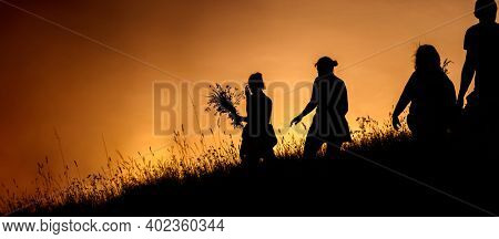 Silhouettes of People picking flowers during midsummer soltice