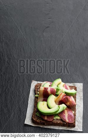 Sandwich  With Plant-based Bacon Rashers And Avocado On Black Stone Background