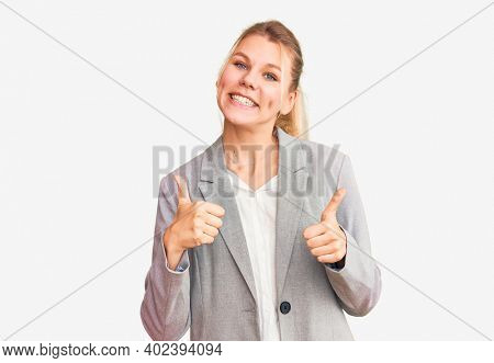 Young beautiful blonde woman wearing elegant jacket success sign doing positive gesture with hand, thumbs up smiling and happy. cheerful expression and winner gesture. 