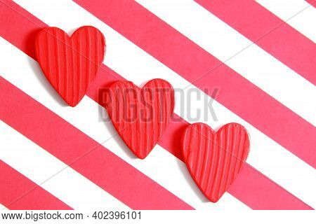 Three Red Wooden Hearts On A White Paper Background With Red Stripes. Creative Greeting Card For Val