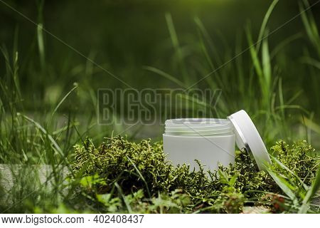 Cosmetics, Skin Care, Beauty, Body Treatment Concept. Open White Cosmetic Jar, Tube, Bottle On Green