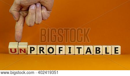 Profitable Or Unprofitable Symbol. Businessman Hand Turns Cubes And Changes Word 'unprofitable' To '