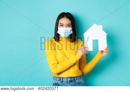 Covid-19, Pandemic And Real Estate Concept. Young Asian Woman In Yellow Clothes Showing Paper House 