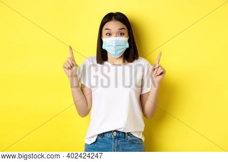 Covid-19, Pandemic And Social Distancing Concept. Young Asian Woman In White T-shirt And Medical Mas
