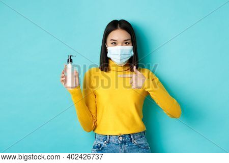 Covid-19, Social Distancing And Pandemic Concept. Cheerful Asian Woman Showing Hand Sanitizer, Recom
