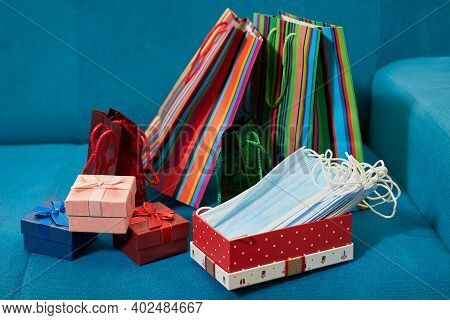 Red Gift Box Full Of Medical Masks. Gift Shopping Paper Bags On The Turquoise Sofa At The Mall.