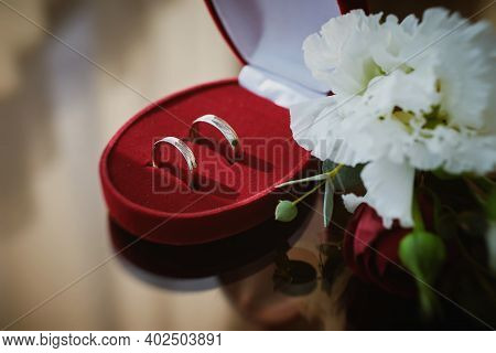 Close Up View Of Wedding Rings In A Red Velvet Box And White Flowers On A Glass Table In The Hotel R