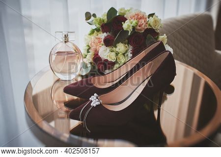 Bridal Accessories On A Glass Table In A Hotel Room. Wedding Set Of The Bride. Wine Red Shoes, Perfu