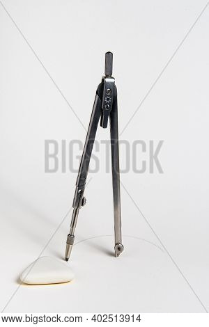 A Vintage Compass Stands With Its Foot In The Center And Draws A Circle On A White Sheet Of Paper, A