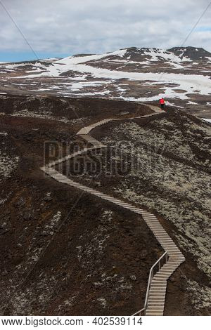 Tourist Standing On Wooden Stairway Staircase Steps Of Grabrok Volcano Lava Crater Rim In Borgarfjor