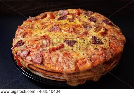 Italian Pizza Cake With Four Layers Full Of Grilled Salami, Ham And Moose Sausage. Black Background.