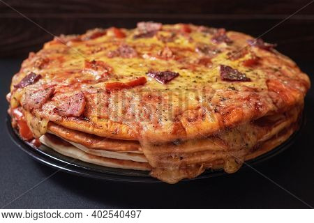 Italian Pizza Cake With Four Layers Full Of Grilled Salami, Ham And Moose Sausage. Black Background.