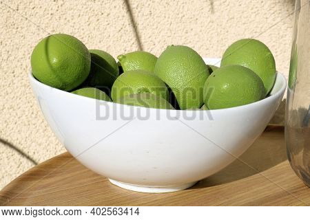 Bowl Filled With Limes Besides A Drinking Water Pot On An Outdoor Table At A Patio Taken In A Reside