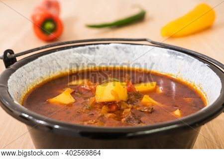 Hungarian Beef Goulash Or Gulyas Soup Or Stew Served In A Small Cauldron With Potatoes, Meat, Paprik