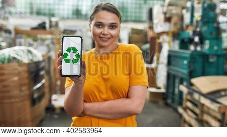 Recycling Sign With Green Arrows On Smartphone Screen Helb By Smiling Caucasian Young Girl Working O