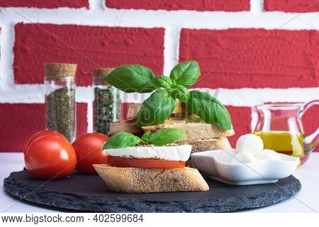 Rapeseed Oil In A Jug, Basil, White Bread Croutons With Mozzarella, Spices And Tomato On A Stone Sta